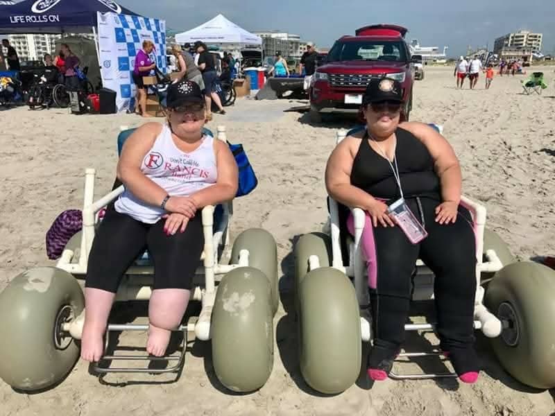 Two members in beach wheelchairs at Life Rolls On