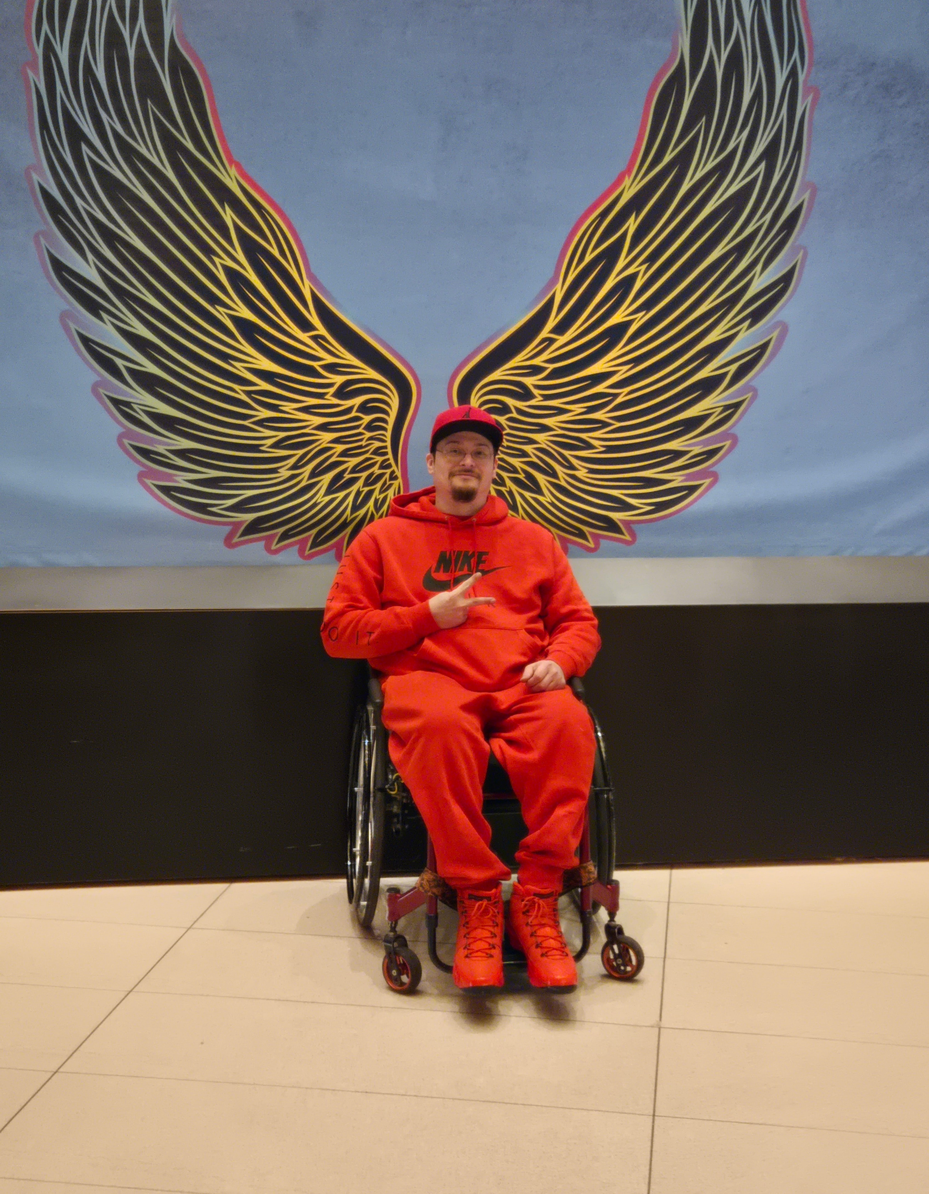 Member posing in front of neon wings mural